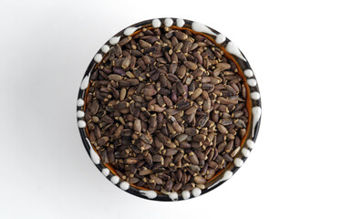 A bunch of seeds in a ceramic bowl. Isolated on white background. Selective focus..
