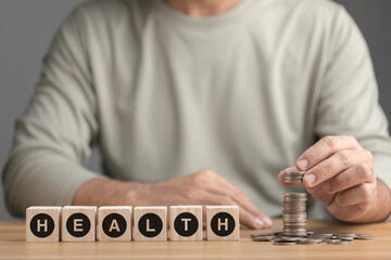 Financial for health concept, The idea of saving money for health and life, Man adding coin to stack on desk. Health, health check up or saving money concept.
