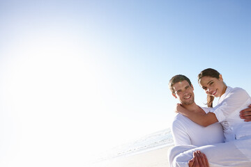 The young couple enjoying the sun. a young man carrying his girlfriend along a beach.