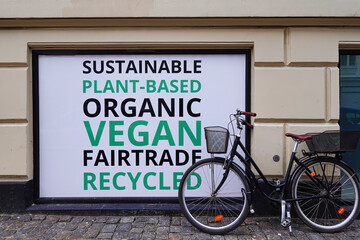 Copenhagen, Denmark A bicycle is parked in front of a store window with a sign saying; Sustainable, plant-based, organic, vegan, fairtrade, recycled.