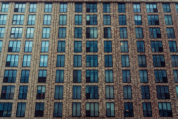Fototapeta premium A high-rise building with glass windows, another house is reflected in the windows
