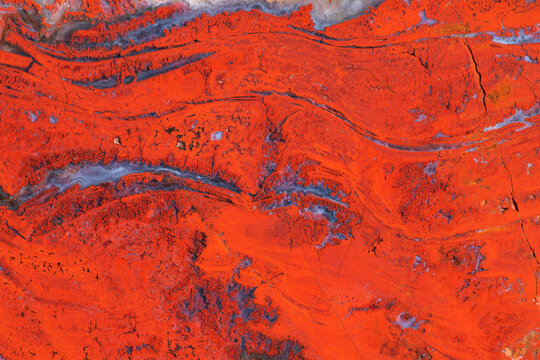 Full-screen texture of natural red jasper with wavy veins of blue chalcedony.