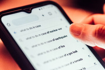 Close up back view of woman searching dystopian themes as search engine produces predictive text