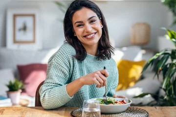Fotobehang Beautiful smiling woman eating healthy while looking at camera at home. © nenetus