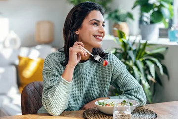 Fotobehang Kruidenier Beautiful smiling woman eating healthy salad at home.  © nenetus