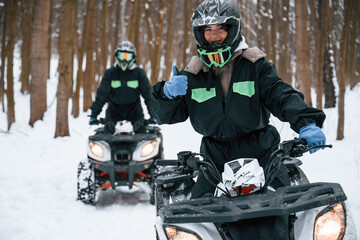 Fototapeta na wymiar Woman with her friend. Two people are riding ATV in the winter forest