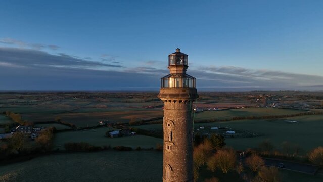 drone shot at sunrise tracking away from spire of lloyd, county meath, ireland
