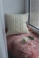 Soft comfortable beautiful knitted pillow on the window