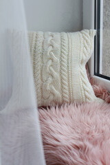 Soft comfortable beautiful knitted pillow on the window