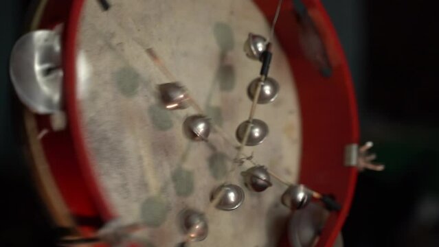 Old tambourine with leather membrane and bells close-up. Playing the tambourine in the dark
