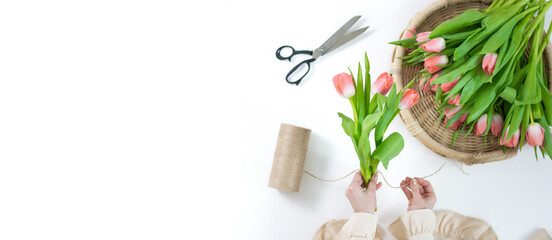 florist's hands create a bouquet of spring tulips on a white background. The process of creating...