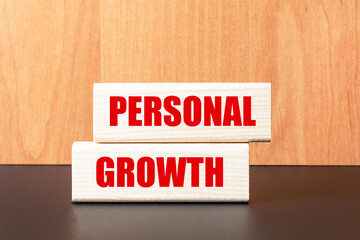 Two wooden blocks with the text PERSONAL GROWTH on a light wooden background