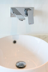 Hygienic wash basin with chrome faucet on bathroom.White washbasin with faucet on marble tile countertop in modern bathroom. Copy space and nobody.