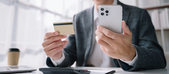 Closeup man holding hand smartphone. Businessman use credit card online payments shopping touching screen mobile phone name numbers.