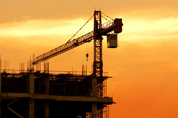 Obraz premium Silhouette construction site on sunset in evening time.Engineer and worker on building site.Construction sites and cranes are working in the industry new building business.