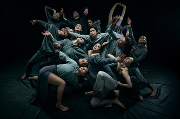 Group of young expressive talented people dancing contemp against black studio background. Concept...