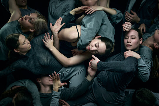 Close-up. Support and chaos. Group of young people, male and female dancers performing against black studio background. Modern freestyle dance, contemporary art, movements, hobby, creative lifestyle