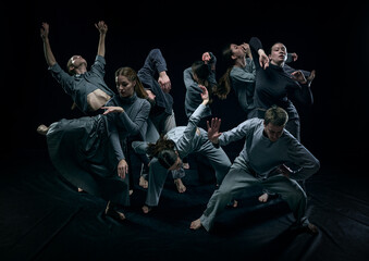Fototapeta na wymiar Group of young men and women contemp dancers performing against black studio background. Concept of modern freestyle dance, contemporary art, movements, hobby and creative lifestyle
