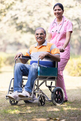 Female nurse with senior man in wheelchair admiring view at park