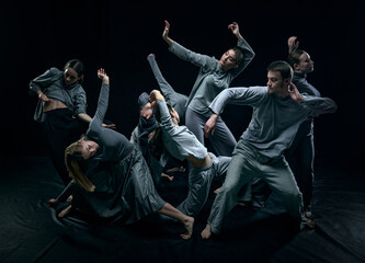 Chaos inside. Group of artistic young people dancing against black studio background. Performance. Concept of modern freestyle dance, contemporary art, movements, hobby and creative lifestyle