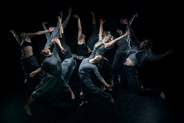 Top view. Expressive contemp dance. Group of young people dancing against black studio background. Concept of modern freestyle dance, contemporary art, movements, hobby and creative lifestyle