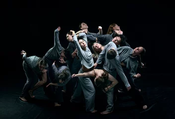 Fotobehang Group of young people in gray stage costumes making performance, dancing against black studio background. Concept of modern freestyle dance, contemporary art, movements, hobby and creative lifestyle © master1305