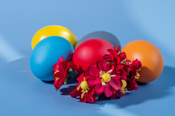 Colorful eggs, symbolizing Easter, on a colorful background and flowers