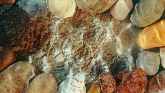 Top down view seabed background, sea floor beach sand ripple of water waves reflection, shells and stones. Yellow sandy bottom surface summer. Underwater seafloor close-up. Place for title or logo