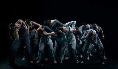 Psychology of dance. Group of young people performing contemp against black studio background....