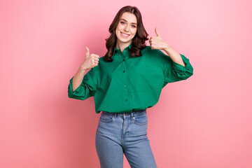 Photo of satisfied pleasant good mood woman with wavy hairdo dressed green shirt showing thumbs up nice work isolated on pink background