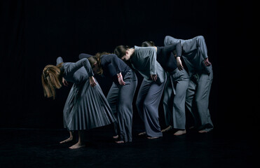 Inner chaos and self-expression. Group of young people dancing contemp against black studio...