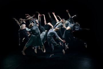 Flying high. Group of young artistic people making freestyle performance, dancing against black...