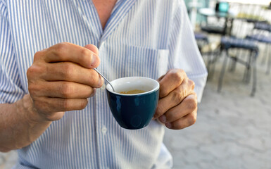 Elderly man drinking espresso coffee at an outdoor cafe