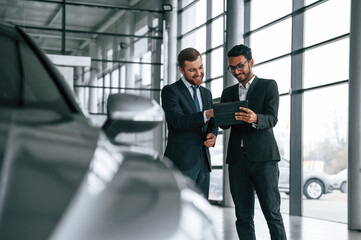 Checking quality of the vehicle. Man is consulting the customer in the car showroom