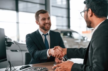 Successful deal. Two businessmen are working together in the car showroom