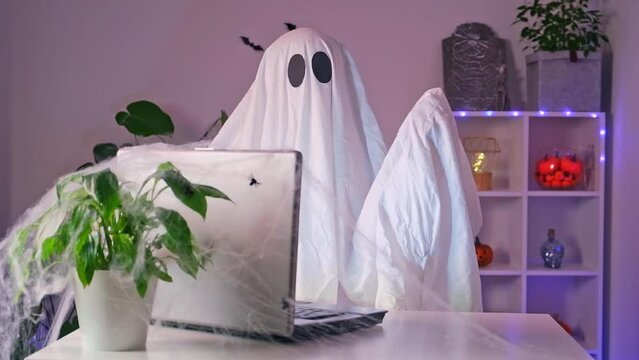 Ghost of Halloween uses laptop surf the Internet, browse online stores, markets. A ghost makes an order from computer for Halloween. Ghost pays for online purchase by credit, bank card.