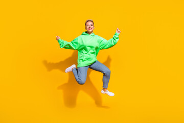 Fototapeta na wymiar Full length portrait of pretty overjoyed person toothy smile jumping isolated on yellow color background
