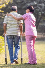 Young Asian woman nurse care giver helping senior old man with mobility walker in garden at home
