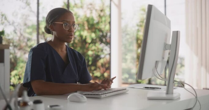Portrait of a Black Female Medical Health Care Professional Working on Desktop Computer in Hospital Office. Clinic Head Nurse is Appointing Prescriptions Online, Updating Electronic Health Records