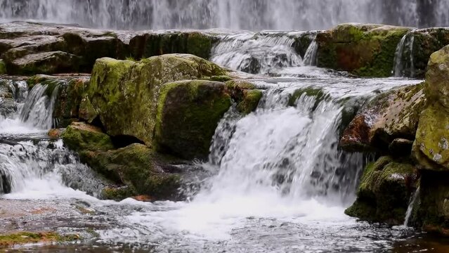 Mountain waterfalls with rocks in the forest, panning, slow motion, close up, hd. ProRes 422 HQ.