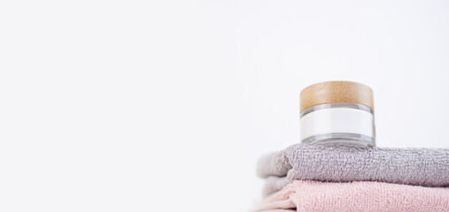set of multicolored bathroom towels and jar of cream isolated on white background. Hygiene itemsю Space for text on the left