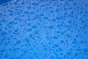 Closup of rain drops on blue car by rainy day - 581445873