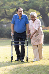 Senior couple walking with walker in the park