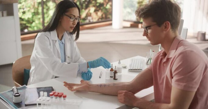 Young Asian Allergist is Conducting a Prick Scratch Test to Diagnose Any Allergic Reaction on a Young Male's Forearm During a Health Check Visit to a Medical Clinic. Female Doctor Working in Hospital