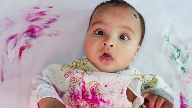 infant paying holi in traditional dress with colors from top angle