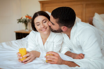 Loving Couple Kissing Drinking Juice Lying In Bed In Hotel