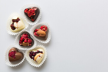 chocolate sweets in the form of a heart with fruits and nuts on a colored background. top view with space for text, holiday concept