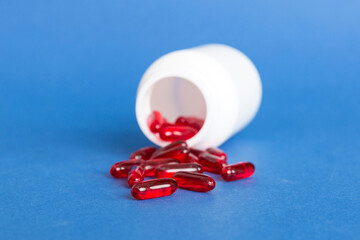 Red pills spilled around a pill bottle. Medicines and prescription pills flat lay background. Red medical capsules