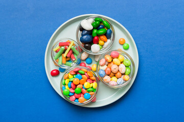 Multicolored candies in a bowl on a colored background. birthday and holiday concept. Top view with copy space
