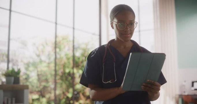 Young Female Doctor Wearing Stylish Glasses, Working on Tablet Computer in Her Office. Beautiful African Medical Health Care Professional Working with Test Results, Patient Treatment Planning
